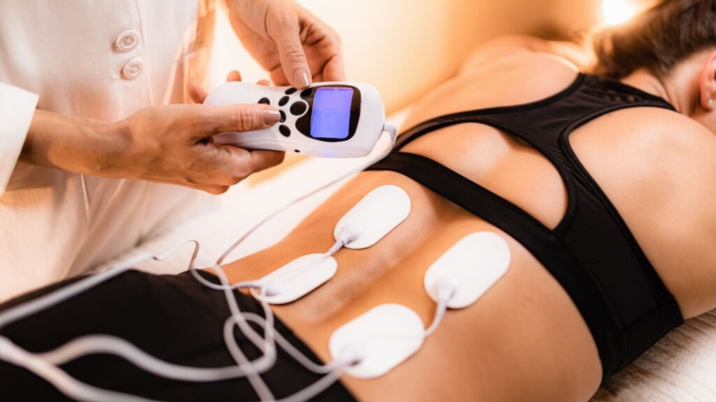Person receiving electrotherapy treatment with electrodes on their back.