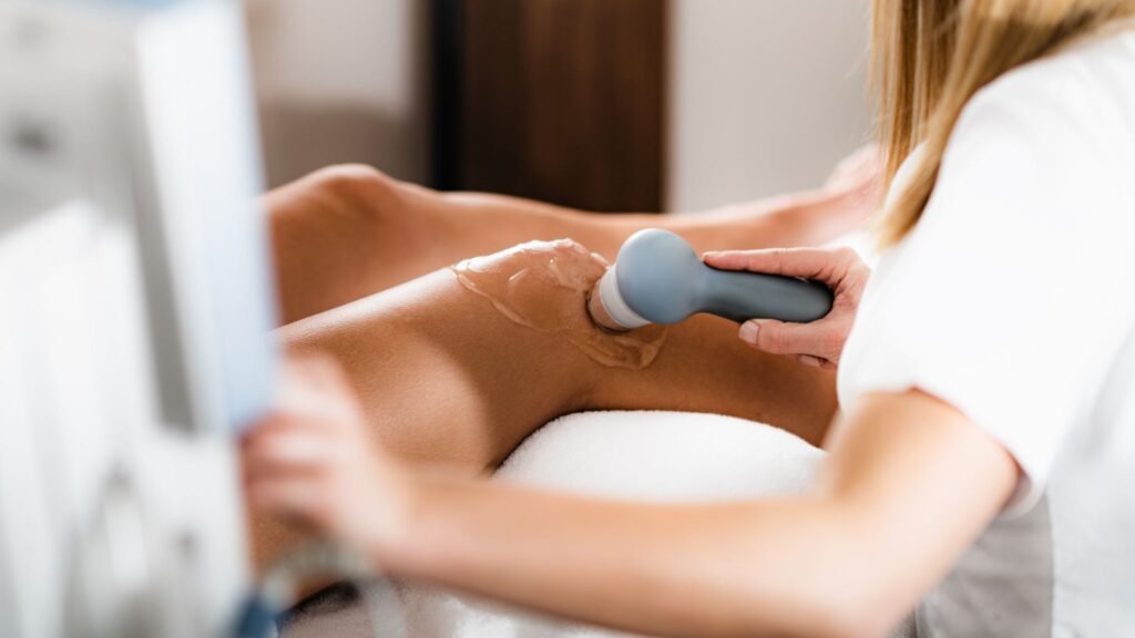 Therapist using an ultrasound device on a patient's leg.