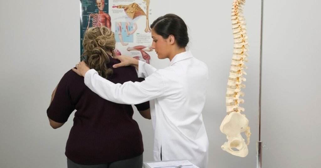 chiropractor-evaluating-a-patients-spine-with-anatomical-charts-in-the-background