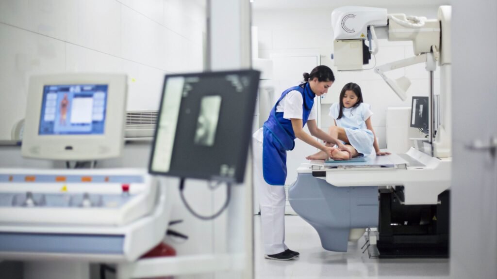 A medical professional is assisting a patient with a digital X-ray procedure in a clinical setting.