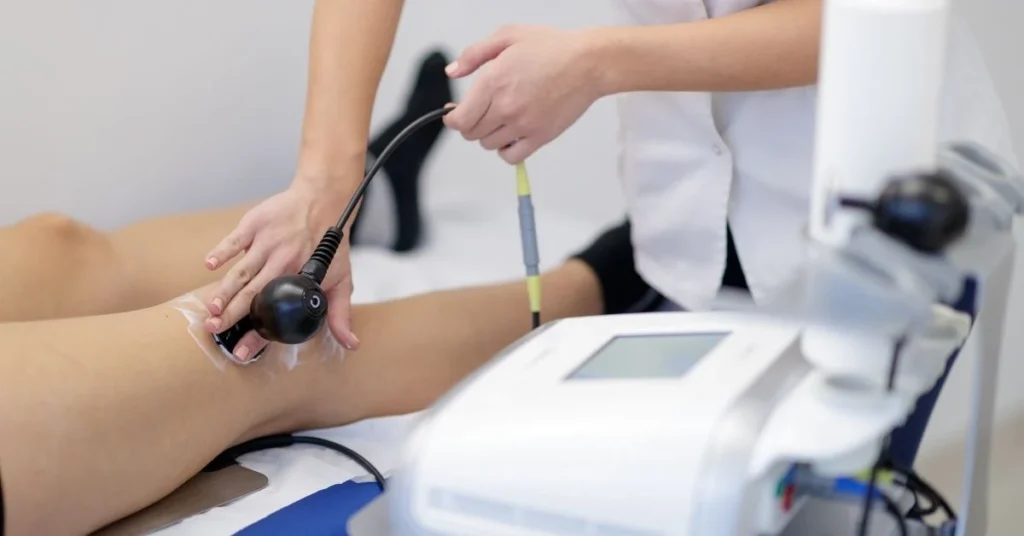 A-chiropractor-in-white-coat-using-a-medical-device-to-treat-a-patient-s-knee-in-a-clinical-setting-focusing-on-laser-therapy.