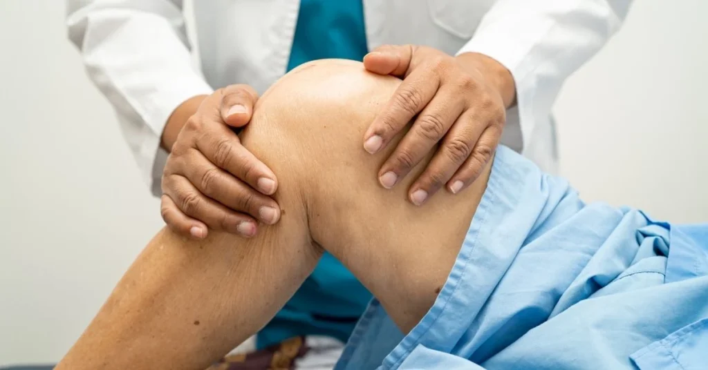 chiropractor examining knee for arthritis care with laser therapy at loucil chiropractic in ives estates and miami gardens