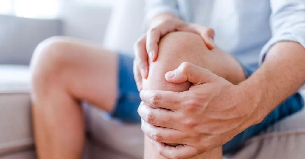 man holding painful knee needing laser therapy for arthritis treatment at loucil chiropractic in ives estates and miami gardens